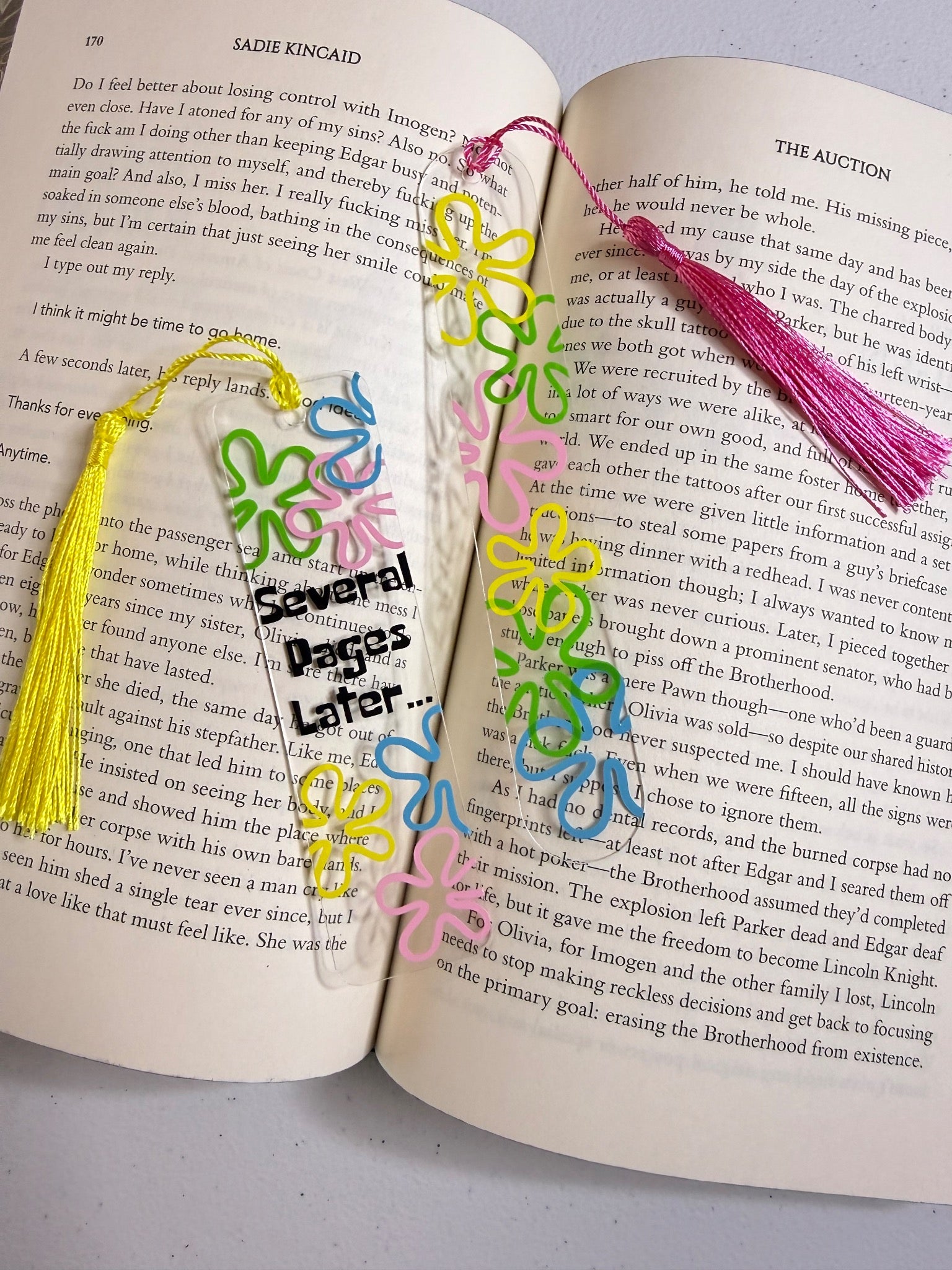 Colorful clear floral bookmark set with tassels shown in an open book