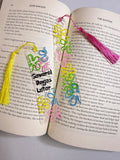 Colorful clear floral bookmark set with tassels shown in an open book