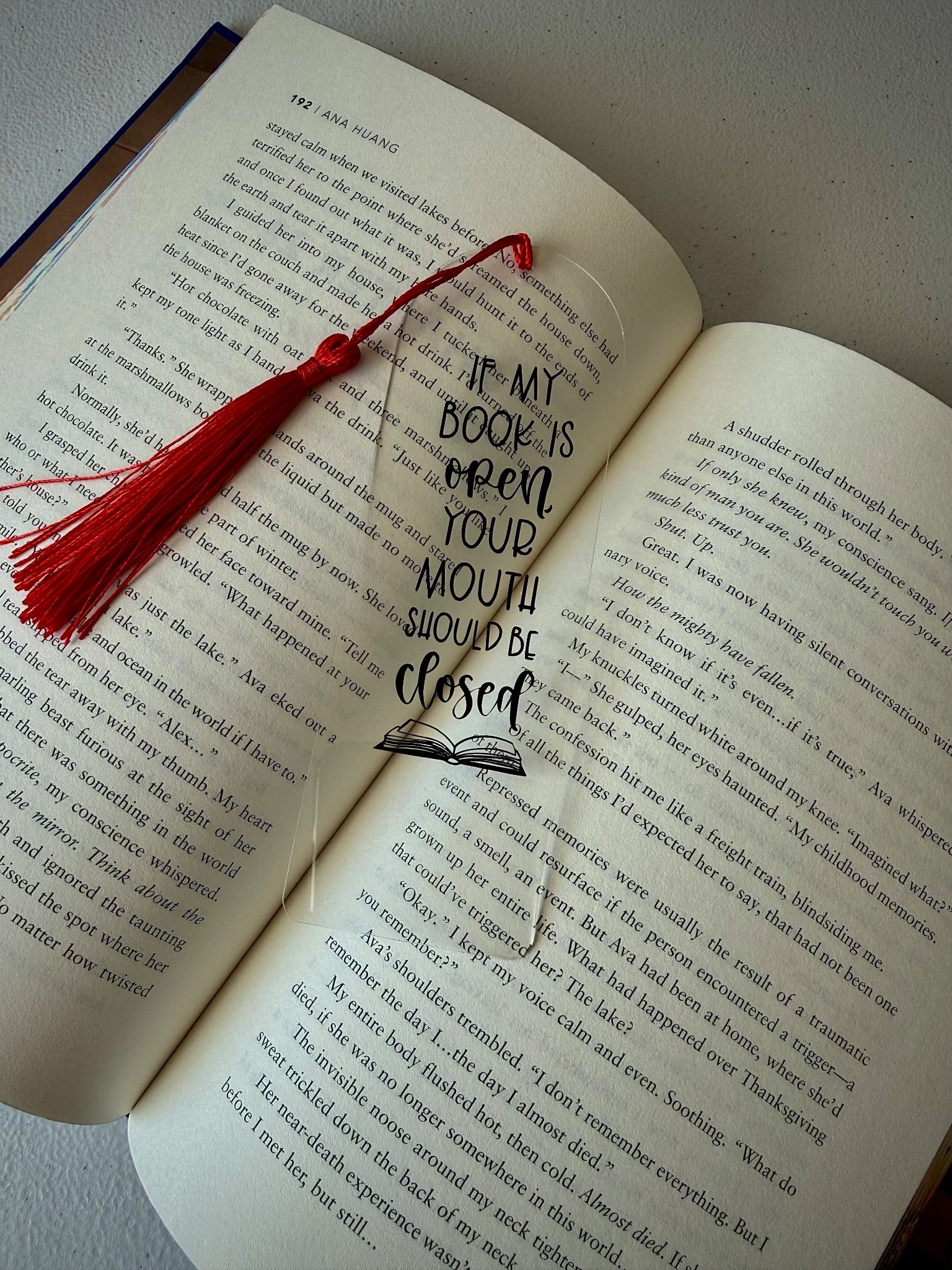 Bookish quote bookmark with red tassel and closed-mouth message