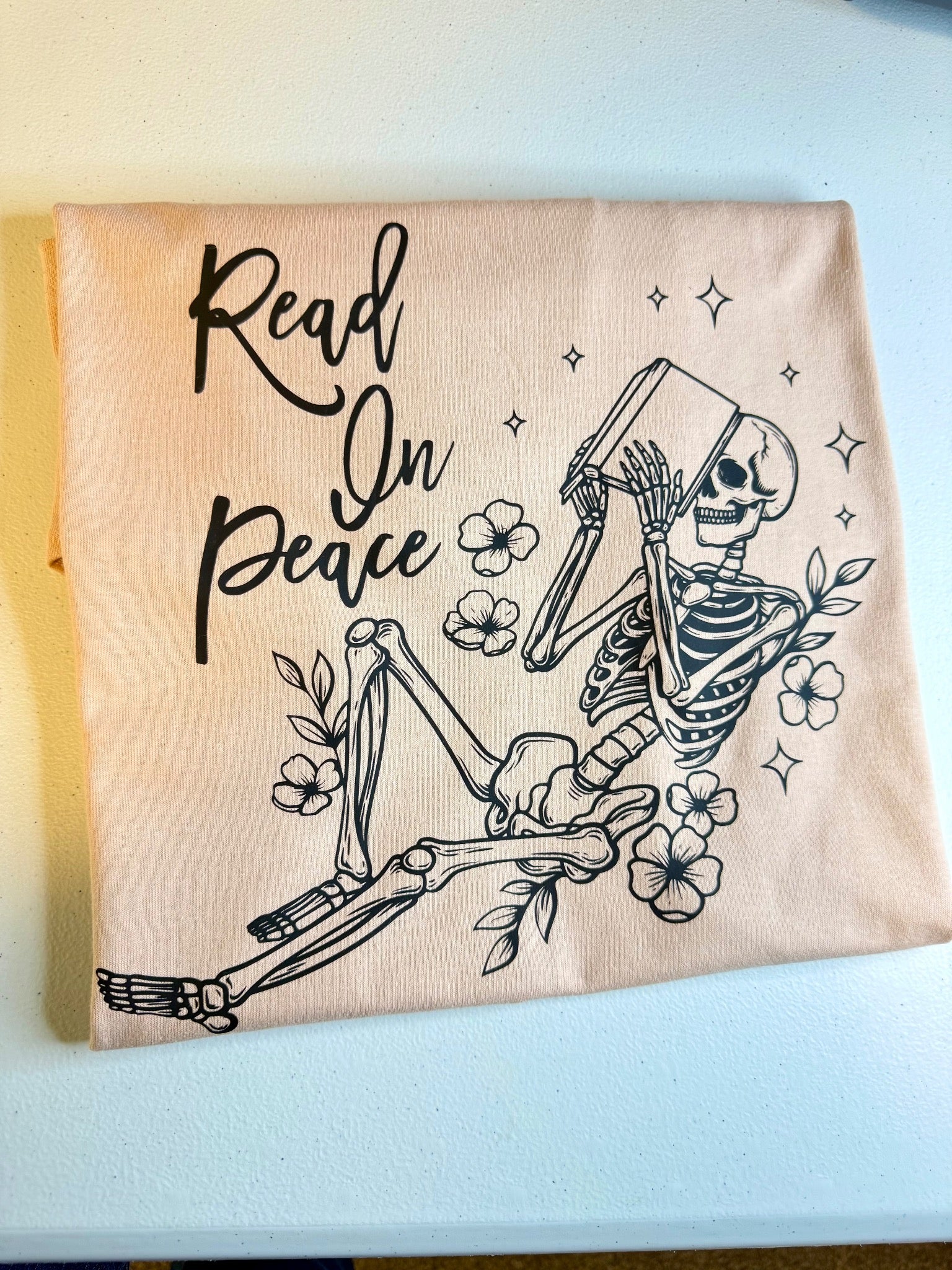 Cream reader T-shirt with Read On Peace skeleton artwork